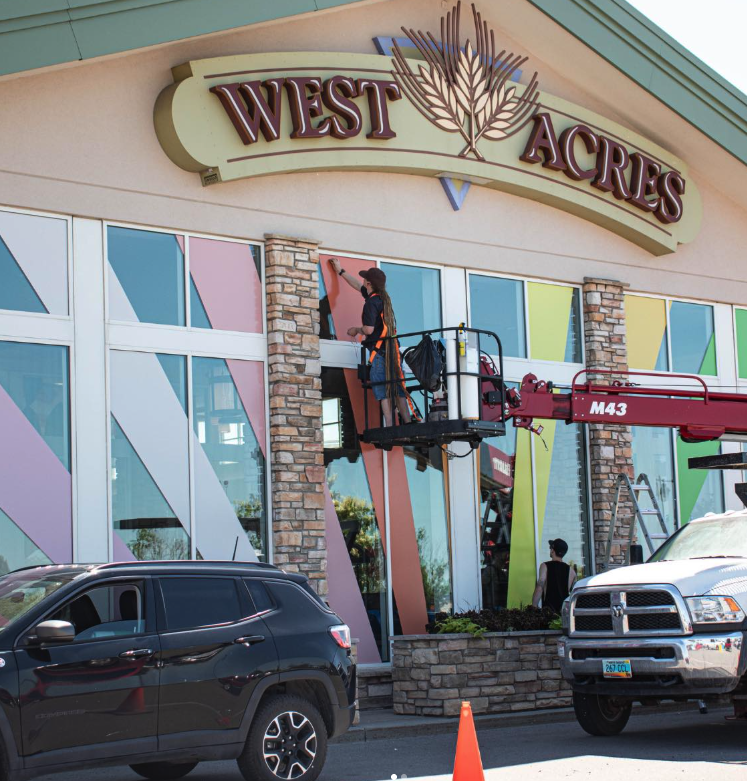 Office Sign Company installer in a lift mounting the West Acres storefront sign