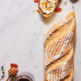 Semolina baguette loaf and slice topped with honey and cream cheese
