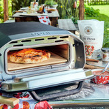 Ooni Volt 12 Electric Pizza Oven on a table with pizza cooking.