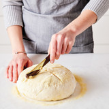 Three cheese semolina bread dough being sliced with the black walnut lame.