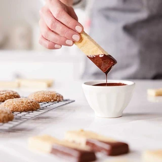 Shortbread cookies being dipped in melted Guittard Semisweet Chocolate Wafers