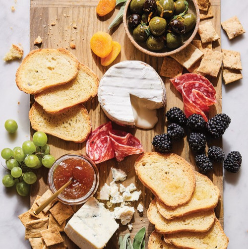 charcuterie board with bread, crackers, olives, grapes, berries, brie, and caramelized onion savory spread