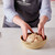 No-knead harvest bread dough being placed in the bread baking bowl.