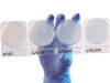 Gloved hand holding a strip of four clear Hardy Diagnostics CompactDry YM plates labeled 1/10 to 1/10,000.
