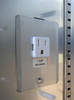 Close-up of a white electrical outlet with a "1 Amp Maximum" label on a metal panel.
