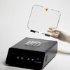 Gloved hand holding the clear lid of a black Labnet digital dry bath incubator loaded with sample tubes.