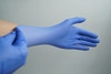 A person putting on blue nitrile examination gloves, viewed from the side.