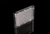 Clear 96-well cell culture plate angled on a reflective black surface, showing a grid of round wells.