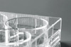 Close-up view of a clear plastic NEST cell culture plate, showing ribbed cylindrical wells inside a rectangular frame.