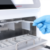 Gloved hand inserting a plastic sample strip into the open chamber of a 4E's nucleic acid extractor.