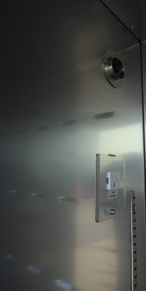 Stainless steel interior of an incubator showing an electrical outlet and access port.