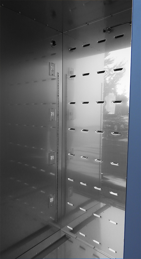 Inside view of a large stainless steel incubator with a vertical array of four electrical outlets on the left wall and
