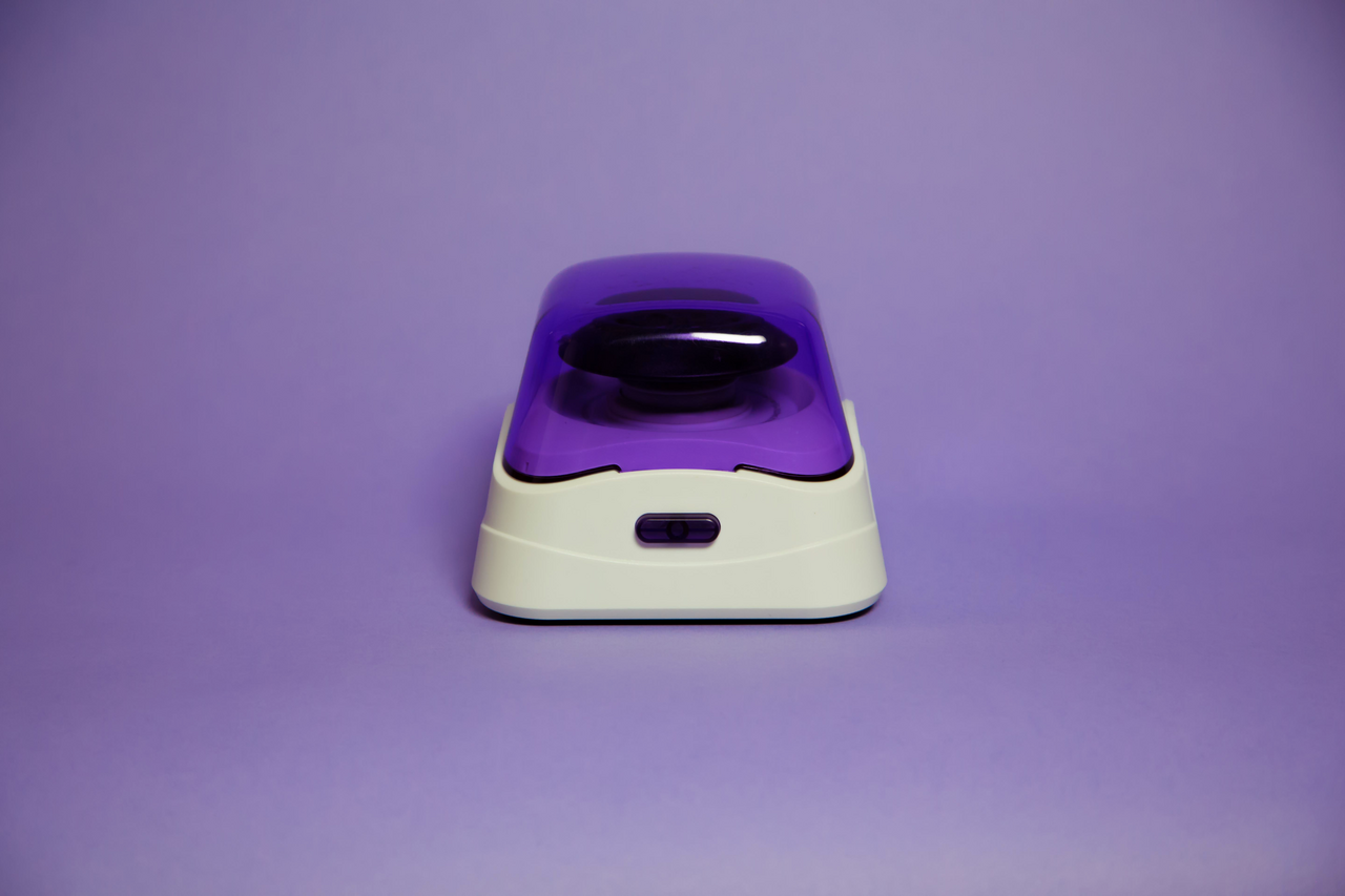 Labnet mini microcentrifuge with a translucent purple lid on a white base, centered on a purple background.