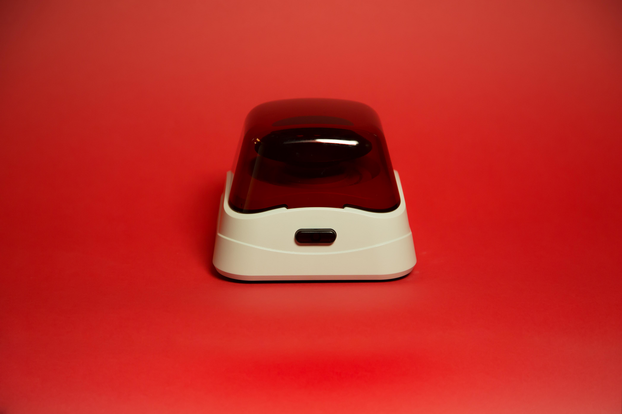Labnet mini microcentrifuge with white base and transparent red lid on red background.