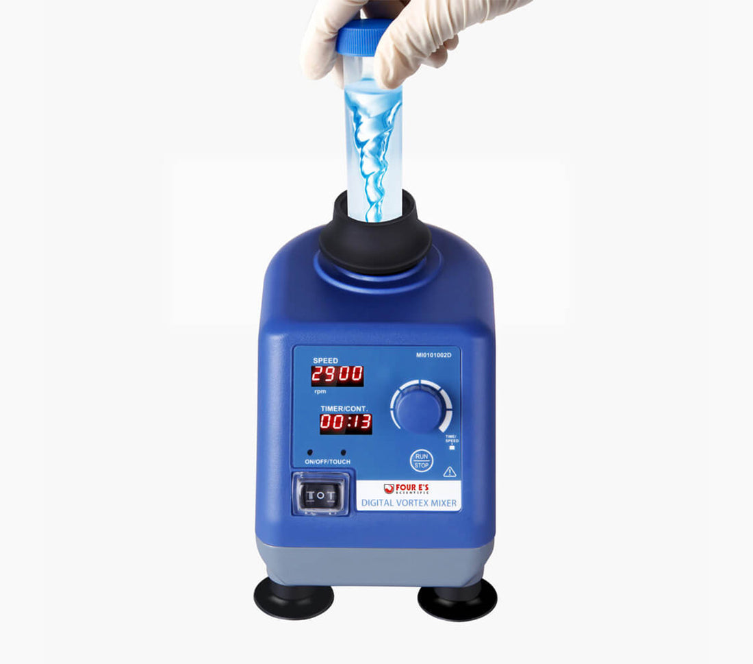 Blue 4E's digital vortex mixer with an LED display, control knob, and a gloved hand holding a mixing tube.