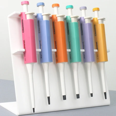 Six colorful adjustable micropipettes in pink, blue, orange, green, purple, and yellow on a white acrylic stand.
