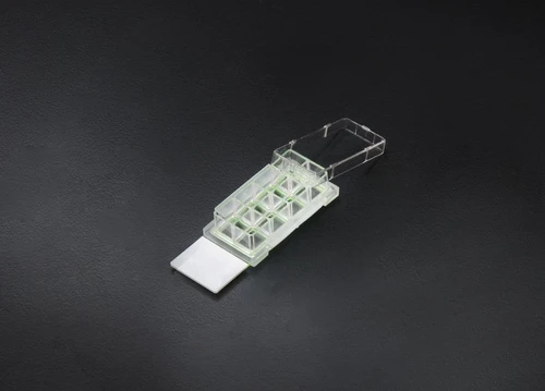 NEST 4-well clear cell culture chamber slide with glass slide and open lid on black surface.