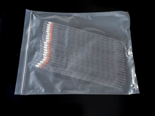 A bulk bag of clear polystyrene 10ml serological pipettes with orange color-coded bands.