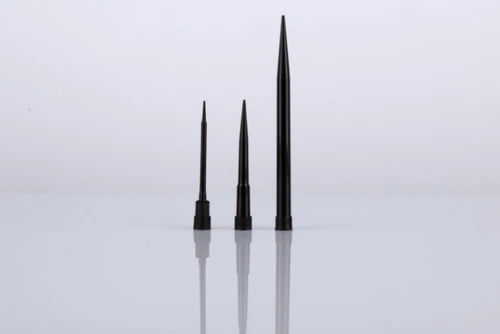 Three black conductive automation pipette tips of varying lengths standing upright on a reflective white surface.