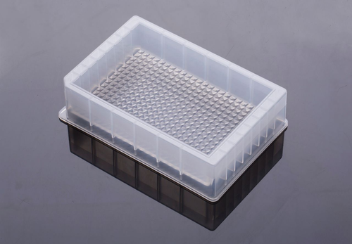 Clear plastic 384-trough single-well reservoir microplate on a reflective surface, viewed from above.