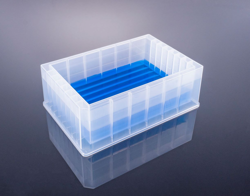 Clear plastic reservoir microplate with blue liquid, viewed from an elevated angle.