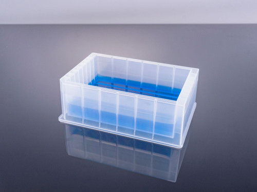 An angled view of a translucent plastic reservoir microplate holding blue liquid, on a reflective surface.