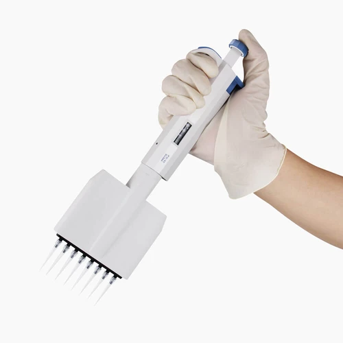 A gloved hand holding a white 8-channel adjustable volume pipette with tips attached.