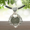 Allende meteorite jewelry 925 sterling silver shown on a black cord chain with dark wood, sun, leaves background.
