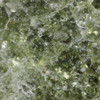 5x close-up reveals moss-green Trinitite, prismatic flares, white, frothy mineral inclusions alongside tiny metallic patches, Sciencemall