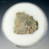 Front view, up close of trinitite green, black, metal, bleb, on a display stand at Sciencemall-USA