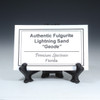 Description tag for fulgurite geode, shown on a black coin mount stand, Sciencemall-USA