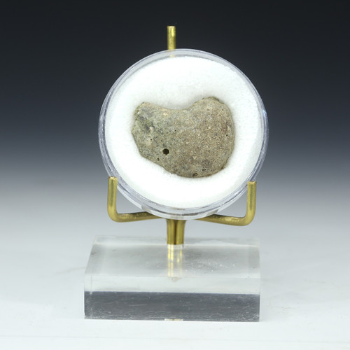 Trinitite green minor black specimen 91807 shown front on a square plexiglass riser with gold prong stand.