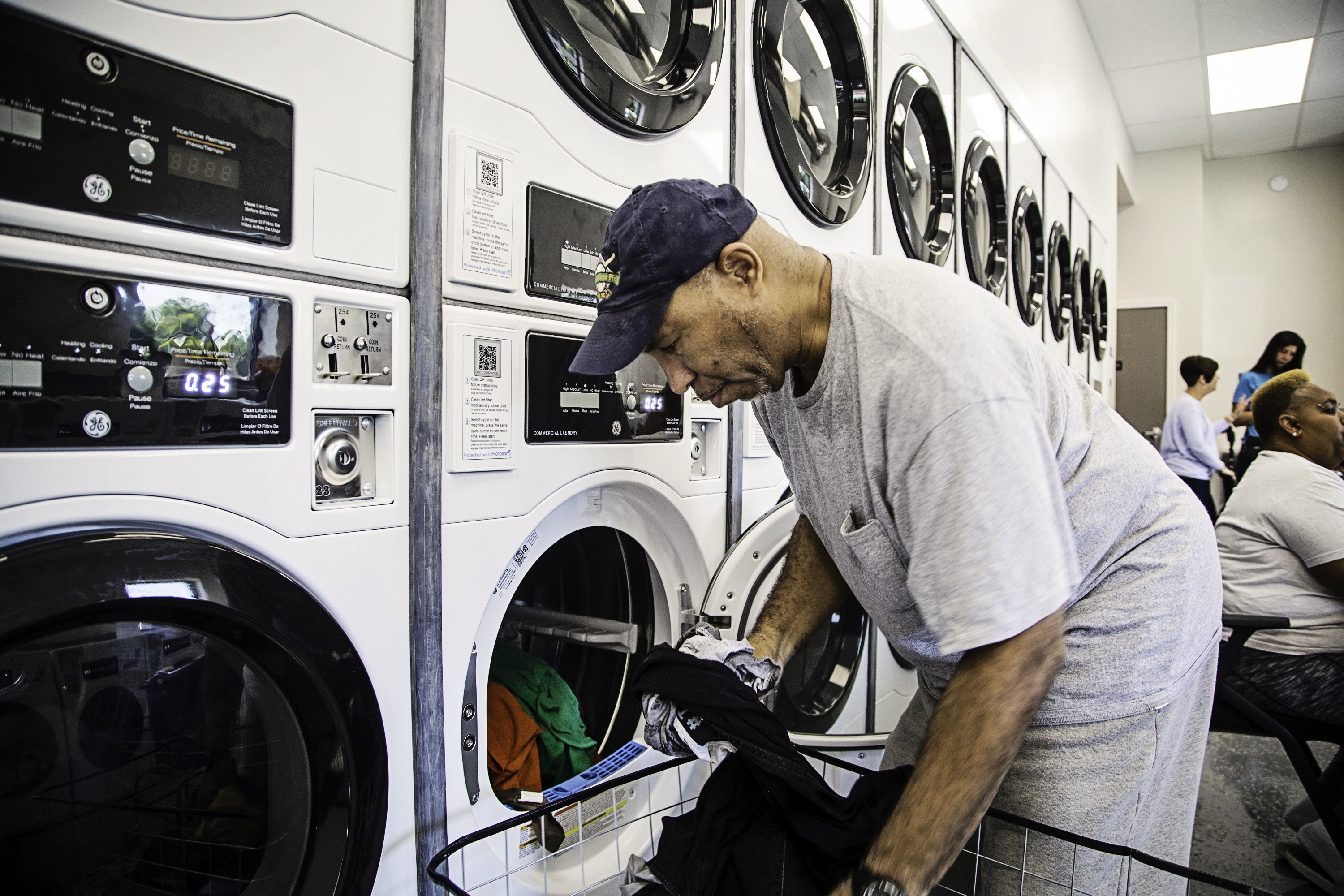 Man loads laundry into one oof many commercial laundry units at the new Smoketown laundry mat