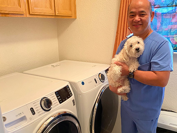 Nursing assistant Roland Cordova and dog pose for a photo next to his new washer and dryer pair.