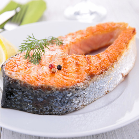 A thick Alaska king salmon steak on a white plate.