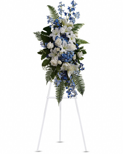 Tranquil blue and white flowers reminiscent of a soft ocean breeze offer comfort. The standing spray presented on an easel includes fragrant white lilies and tropical greenery.
This standing spray includes blue hydrangea and delphinium, white roses and asiatic lilies, plus tropical ferns and leaves.
Orientation: One-Sided