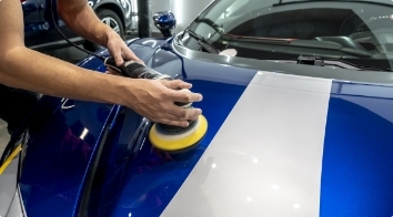 A man applies auto polish from Esoteric Car Care to a car exterior