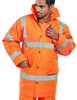 CONSTRUCTOR JACKETS ORANGE L, high-visibility orange jacket with reflective stripes and a hood, worn by a man adjusting the collar.