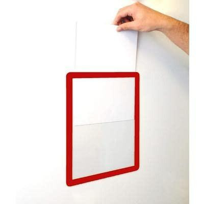 GPC OD-SFD4/10-RED A4 Self Adhesive Document Frame, Red, Pack of 10, being applied to a wall with a hand holding the top corner, showcasing its ease of use and vibrant red color.