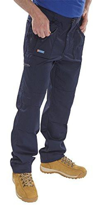 CLICK ACTION WORK TROUSERS NAVY BLUE 44T, a man wearing navy blue work trousers with multiple pockets and reinforced knee areas, paired with tan work boots.