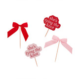 A pack of 12 Pink & Red She's Tying The Knot Satin Bows Food Picks, manufactured by Hootyballoo.