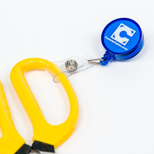 A pair of yellow scissors that are attached to a retractable line within a clip