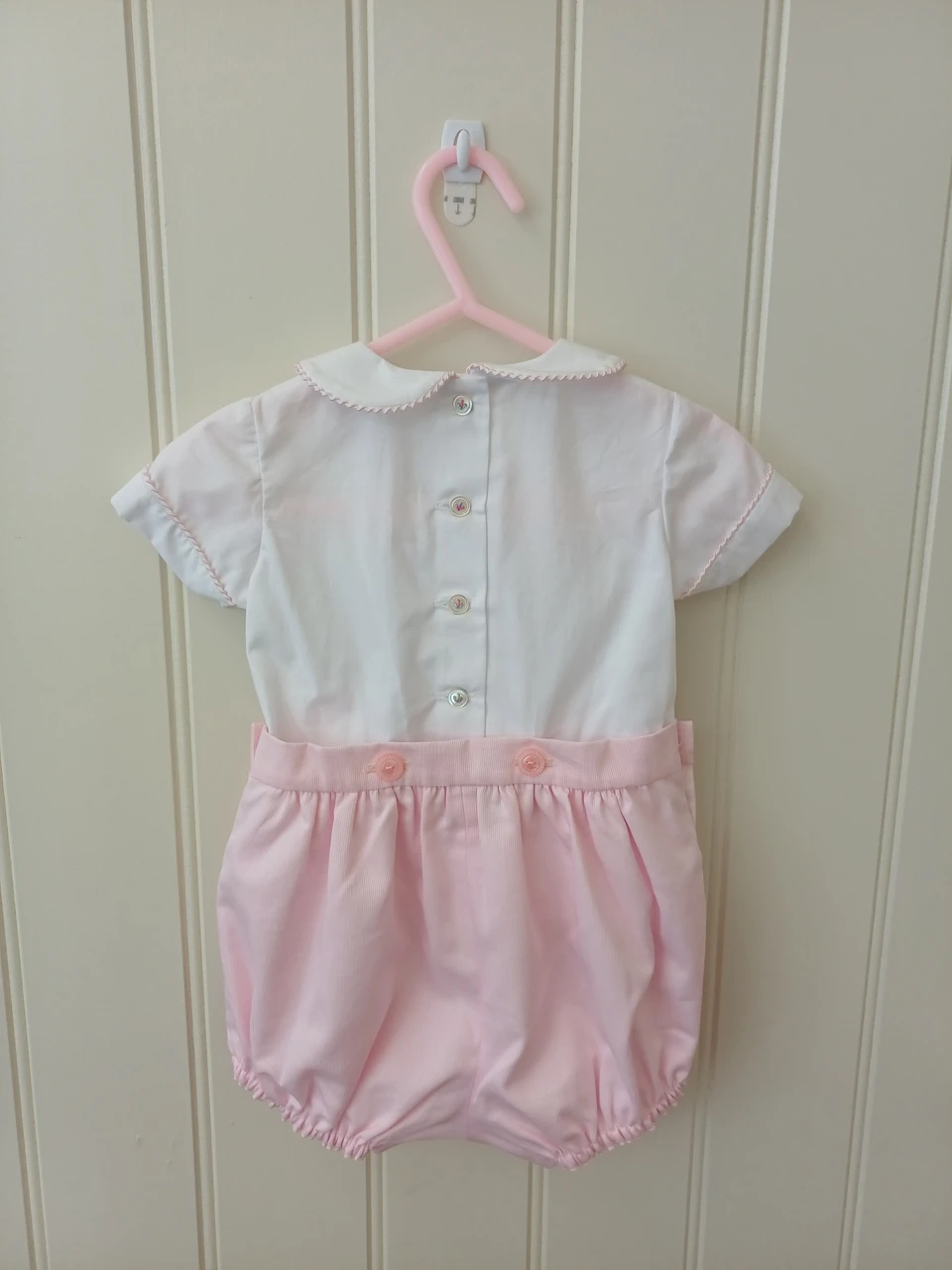 A lovely little button on suit, Size 3-6 month, Multi-coloured hand smocking, Pink whip stitch piping, Pink pique coloured button on pants, Elastic back waistband, Elasticated round the legs, Shirt made from 100% cotton poplin, Pants made from 100% cotton pique, Wash at 30 degrees