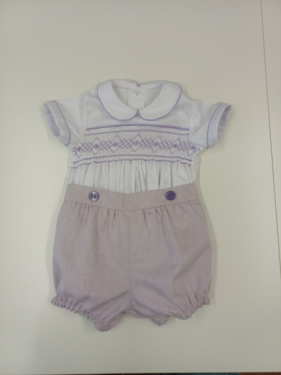 A lovely little button on suit, Size 6-12 month, wisteria coloured hand smocking, wisteria piping, Plum coloured button on pants, Elastic back waistband, Elasticated round the legs, Shirt made from 100% cotton poplin, Pants made from 100% sun-washed chambray, Wash at 30 degrees, 