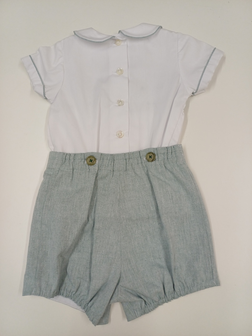 A lovely little button on suit, Size 12-18 month, Green and white coloured hand smocking, Forest Green coloured piping, Forest green coloured button on pants, Elastic back waistband, Elasticated round the back of the legs, Shirt made from 100% cotton poplin, Pants made from 100% sun-washed chambray, Wash at 30 degrees