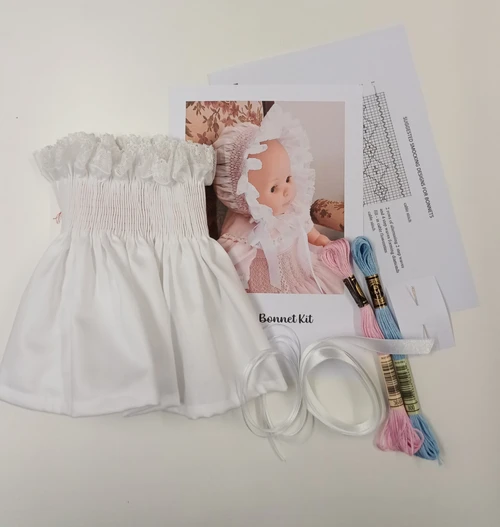 Smocked bonnet kit - kit includes, Pre-pleated bonnet in white sheen sateen,  Back hem and side seams completed, Crewel needle, DMC thread in pink and blue, 2 cm satin ribbon, 3 mm ribbon
This kit assumes you know how to smock