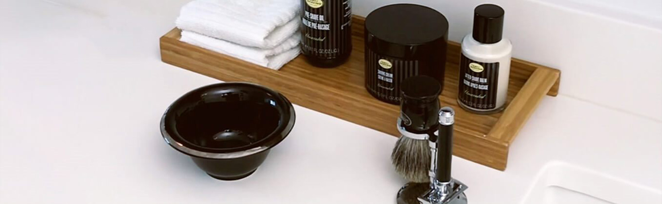 Assorted beard care products including beard brush and water dish on display in a bathroom.