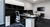 ATDEC AWMS-2-D13 Silver dual monitor desk with adjustable arms and a comfortable ergonomic chair setup.