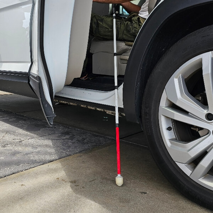 Urban Xplorer mobility cane for the blind fully extended with a passenger sitting in a vehicle getting ready to close the door.