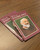 Two booklets on a wood laminate tabletop showing the books Who Is Padre Pio? 